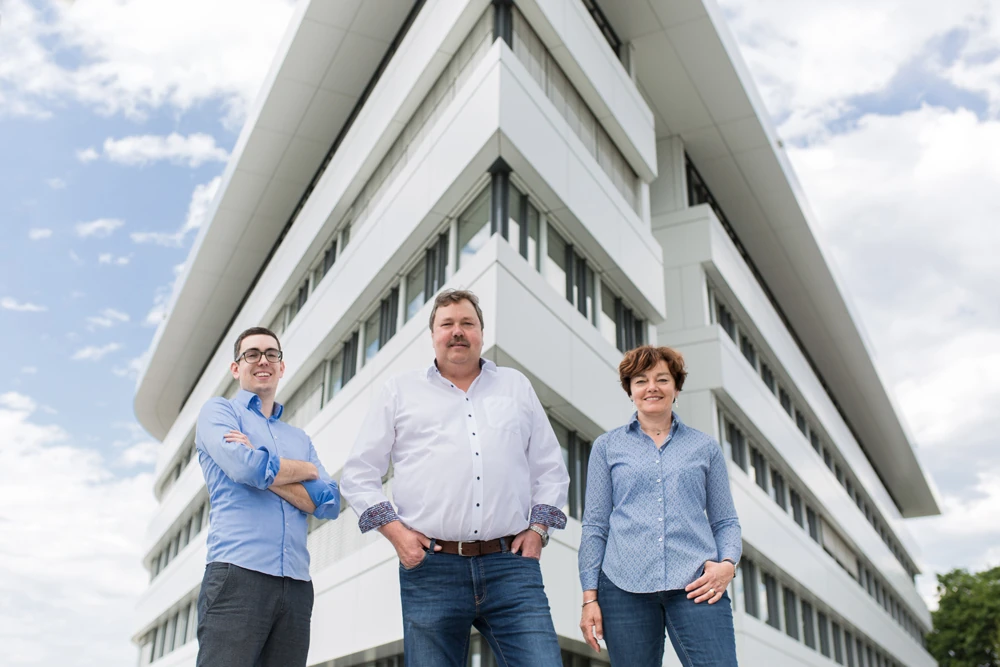 Drei Mitarbeiter vor modernem Bürogebäude, Teamfoto im Außenbereich